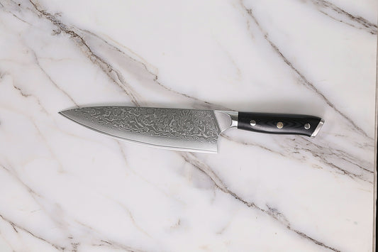 Sharp kitchen knife resting on a marble countertop.