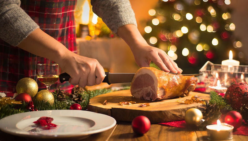 Man carving holiday ham with sharpened knife