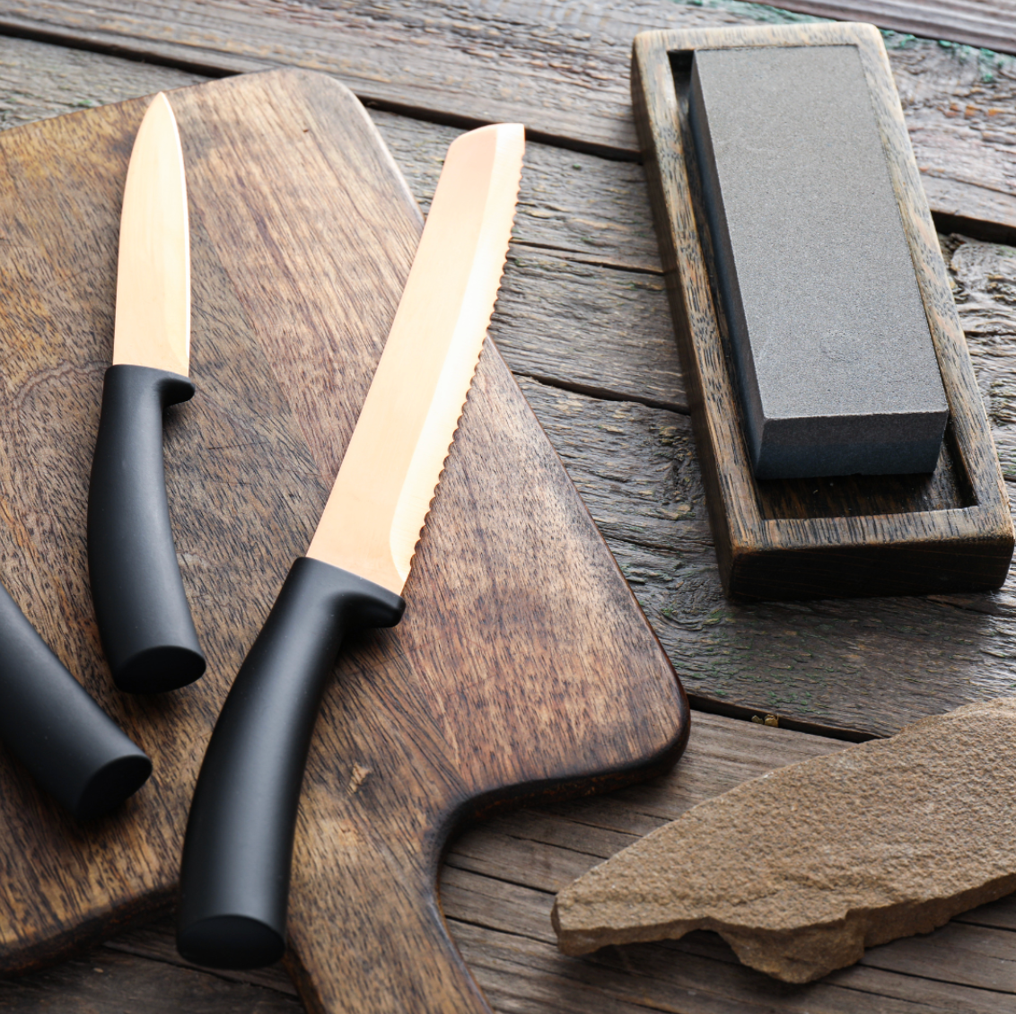 Chef’s knife resting on a wooden cutting board next to a water whetstone, ready for sharpening.