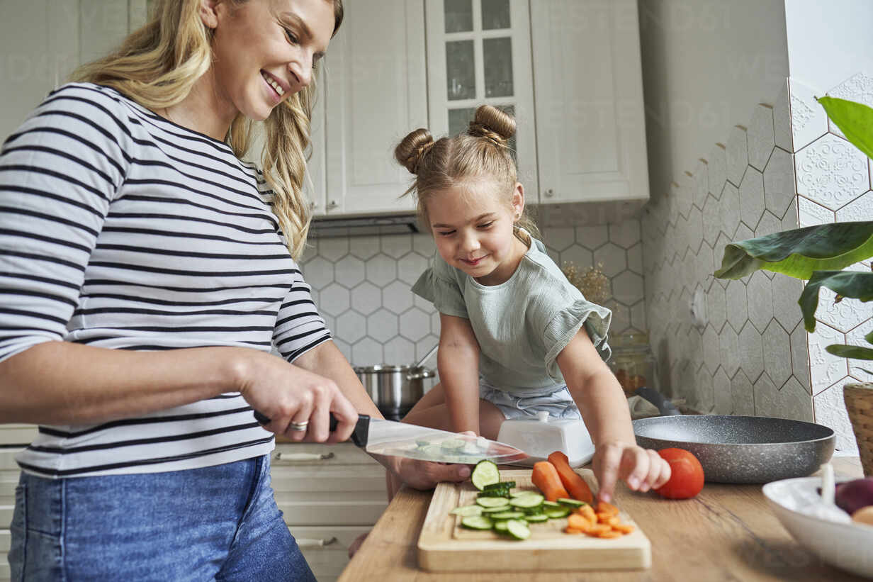 Woman and child in a kitchen preparing food together.